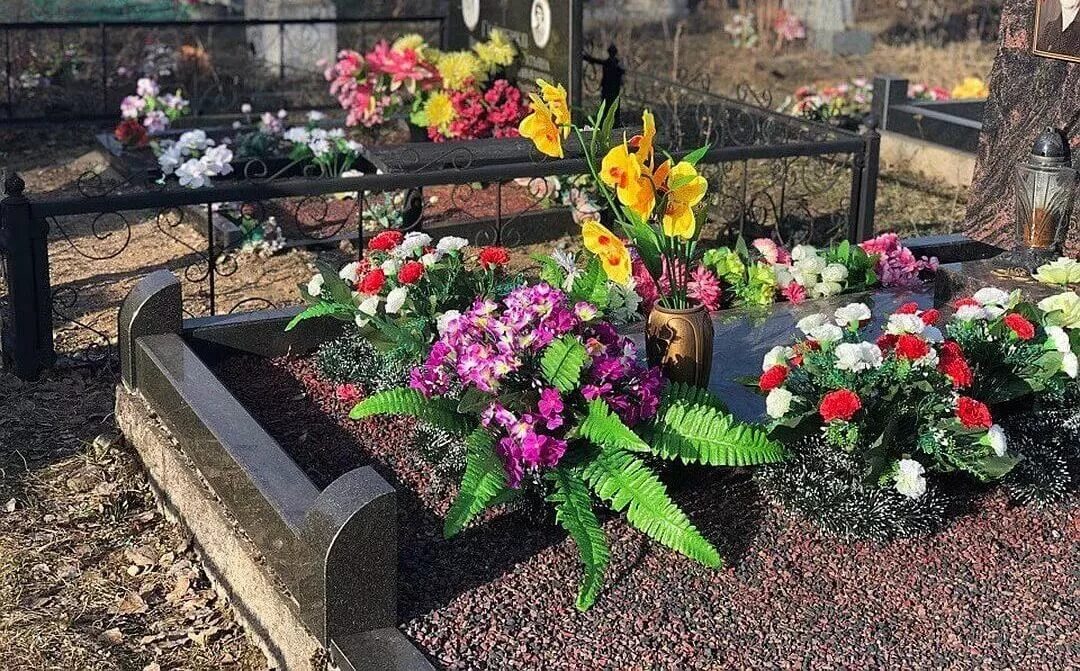 гвоздики, астры, папоротники на могиле, засыпанный щепками посадка цветов на цветнике могилы